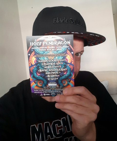 DJ Archive in a Black Sabbath cap holding up the Holy Pendragon flyer, one eye peeking over the top.