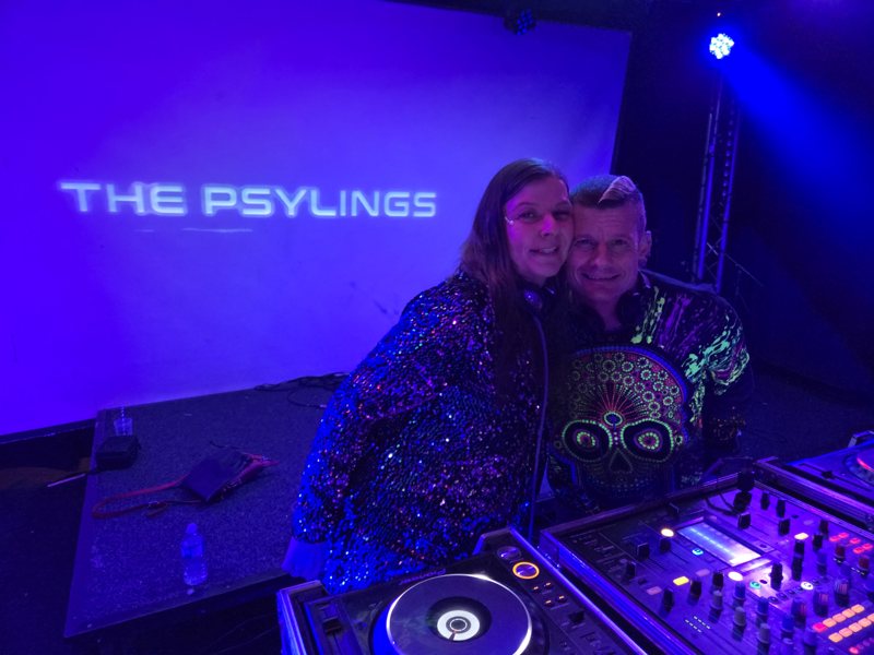 DJ S&M and Frieda, The Psylings, smiling behind the decks with THE PSYLINGS projected on the wall behind them